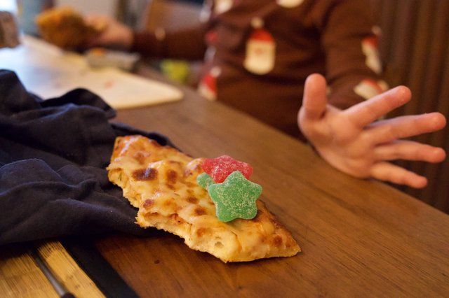 Child's Hand Reaching for Decorated Pizza Slice