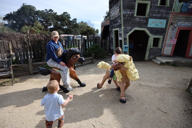 Children Enjoying Whimsical Horse Statues at Theme Park