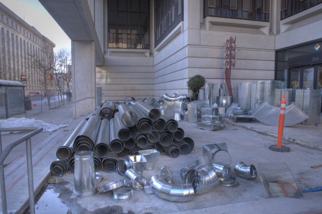Pile of Metal Pipes on the Sidewalk