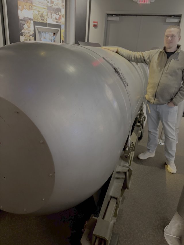 Man Posing with Large Cylindrical Military Equipment