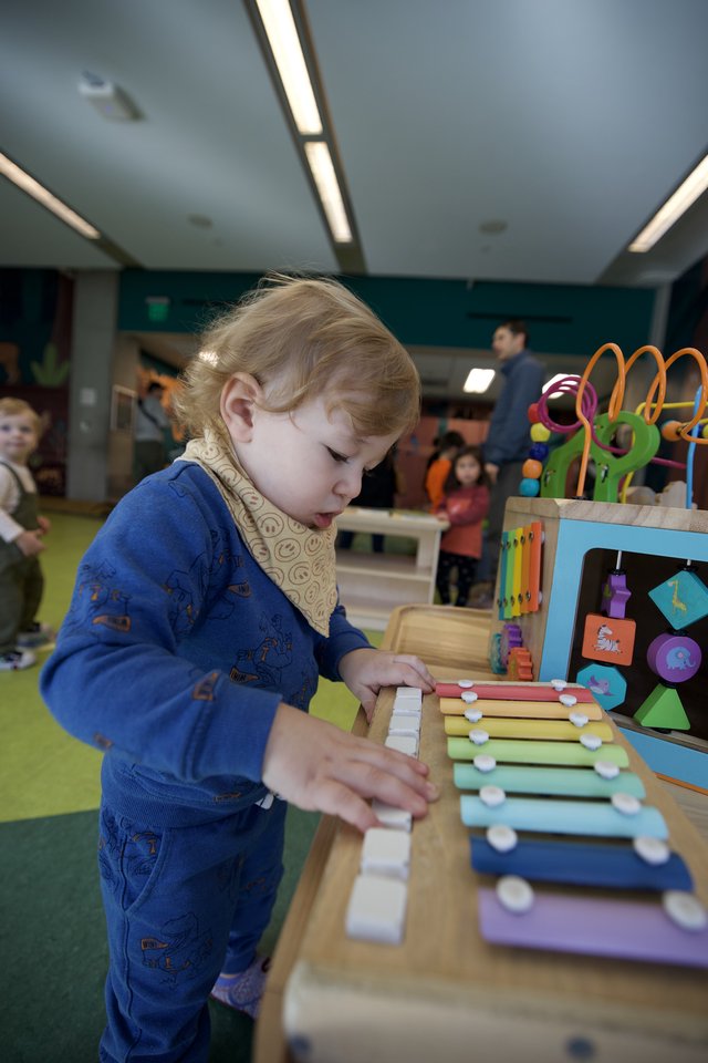 Young Child Exploring Musical Xylophone Toy at Play Center