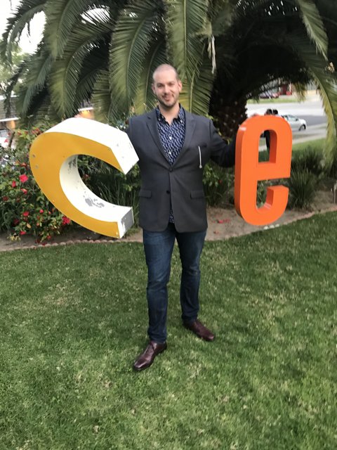 Man holding up a letter C on a grassy lawn