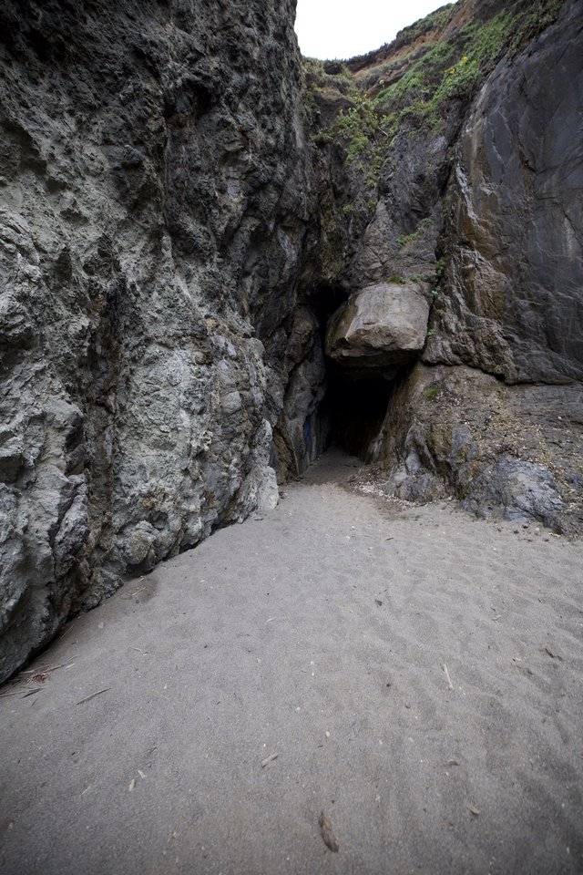 Dark Cave Entrance in Coastal Rock Cliffs