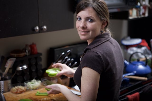 Smiling Woman Chopping Green Peppers in Kitchen