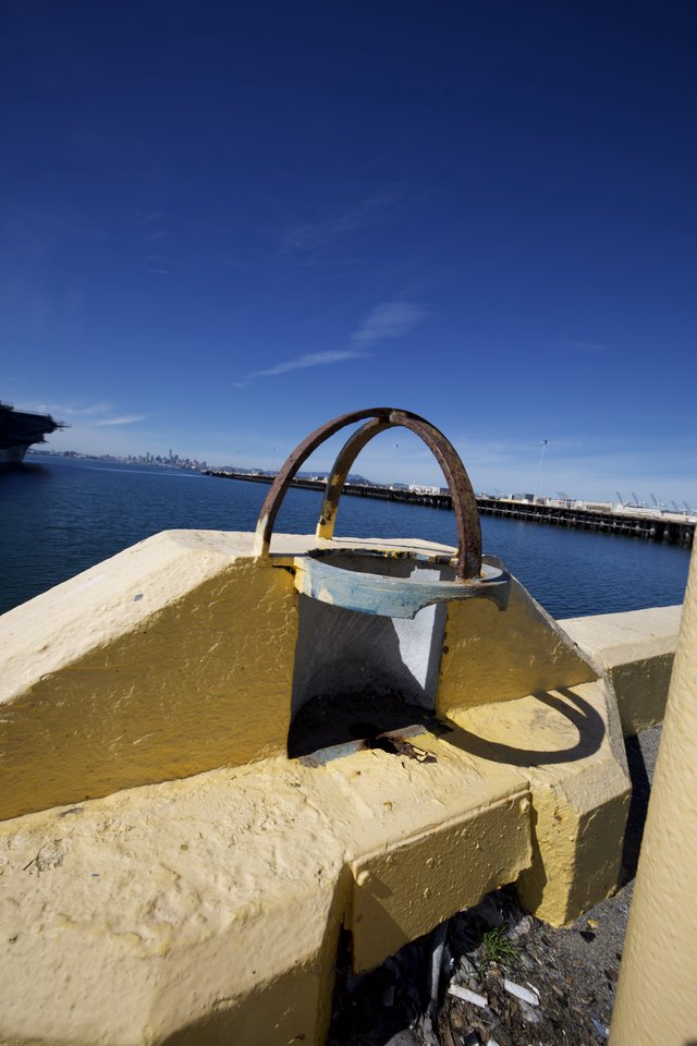 Rusted Mooring Ring on Yellow Painted Bollard at Waterfront