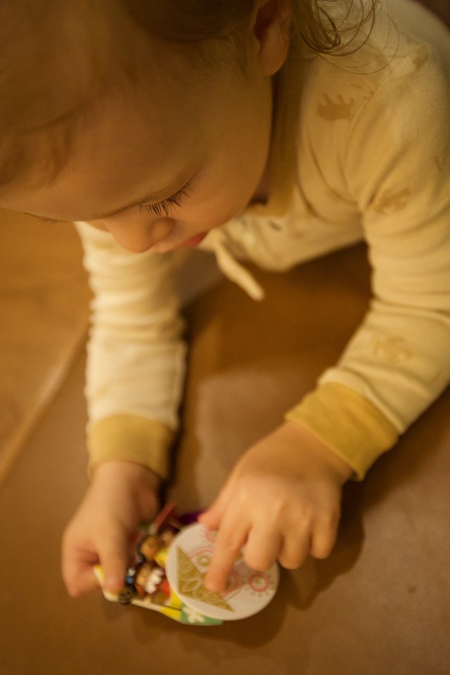Toddler Intently Examining Colorful Book on Wooden Floor