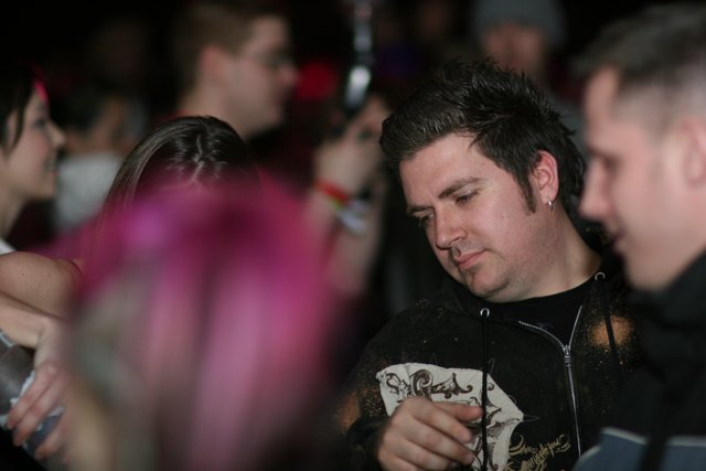 Pink-Haired Man Stands Out in Urban Nightlife Crowd