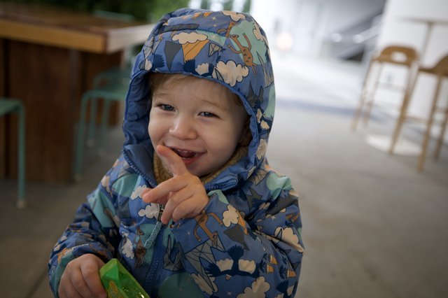 Joyful Toddler in Patterned Rain Jacket at Outdoor Cafe
