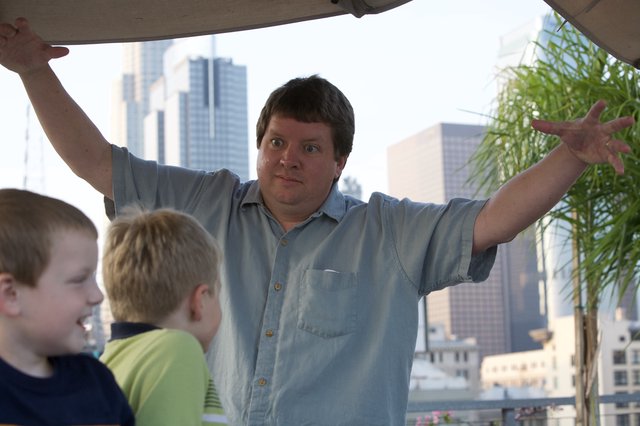 Man Gestures Dramatically with Kids in City