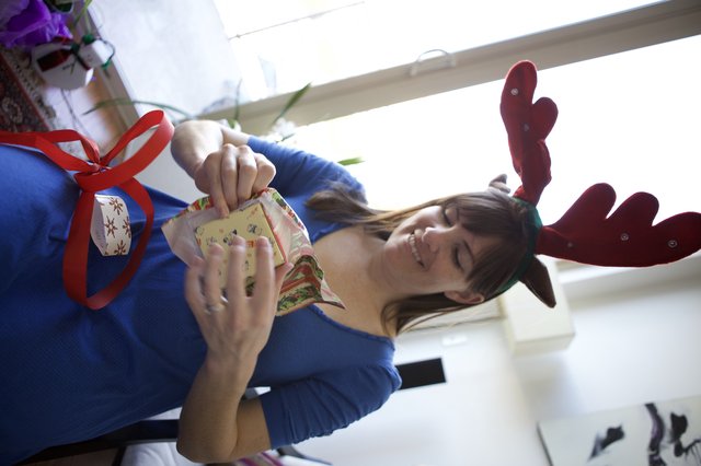 Joyful Woman Unwrapping Christmas Gifts in Reindeer Antlers