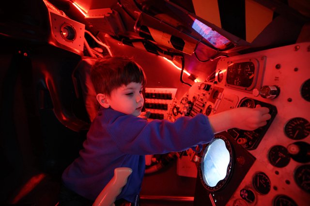 Child Exploring Spacecraft Interior at Space Center
