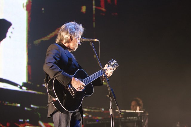 Strumming Solo: A Man with His Acoustic Guitar on Stage