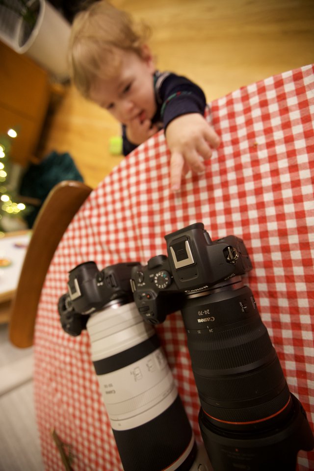 Young Photographer Reaches for Canon Camera on Checkered Table