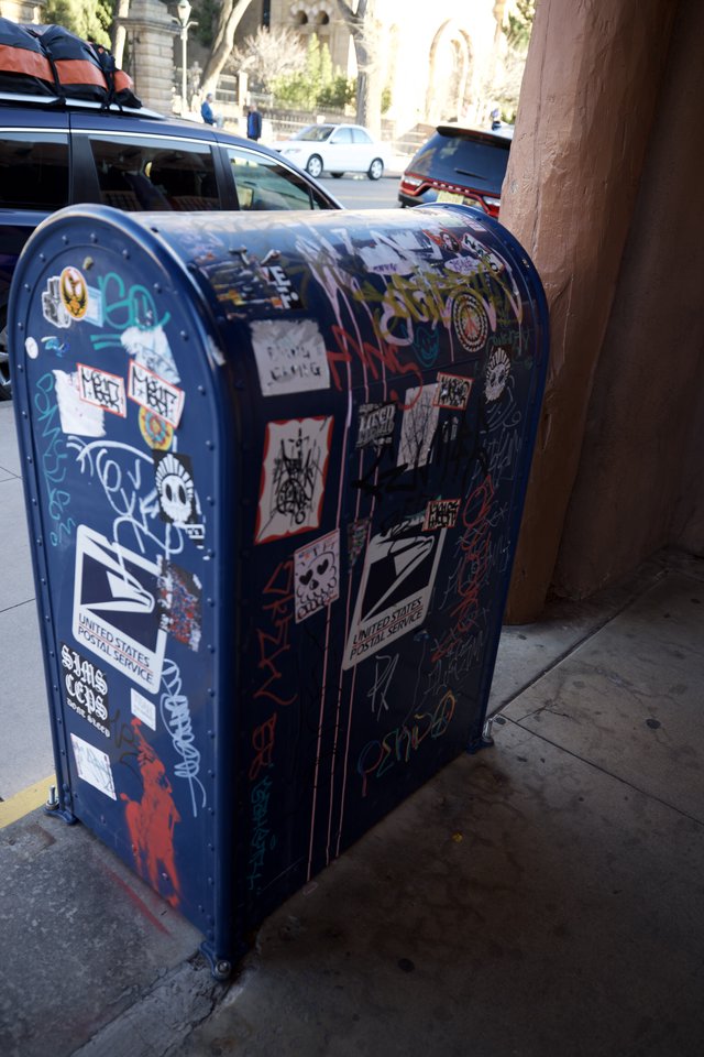 Street Art Sticker-Covered USPS Mailbox on Urban Corner