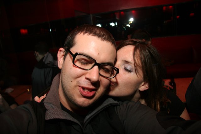 Spontaneous Kiss at a Dimly Lit Nightclub Party