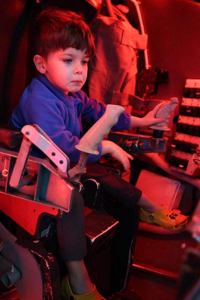 Young Boy Exploring Interactive Exhibit Under Red Lighting