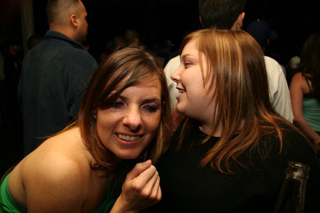 Two Friends Share a Whispered Secret at Nightclub
