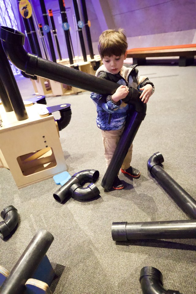 Child Exploring Interactive Pipe Construction Exhibit at Children's Museum