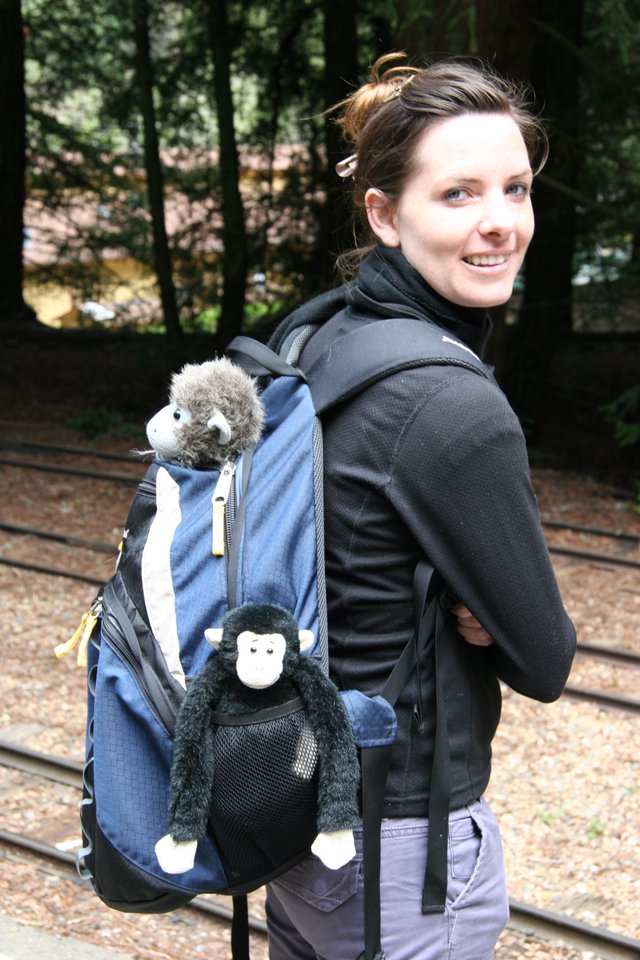 Smiling Woman with Stuffed Monkey Backpack Companions