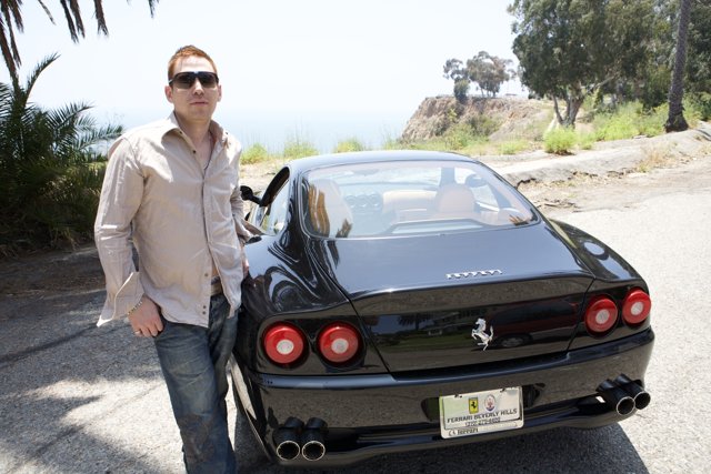 Man Poses Next to Sleek Black Sports Car