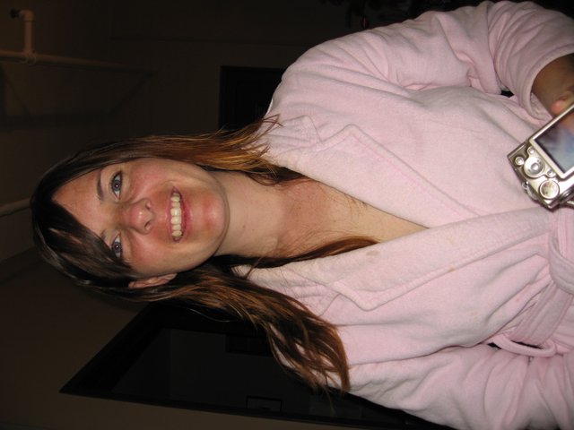 Smiling Woman in Pink Robe Holding Camera