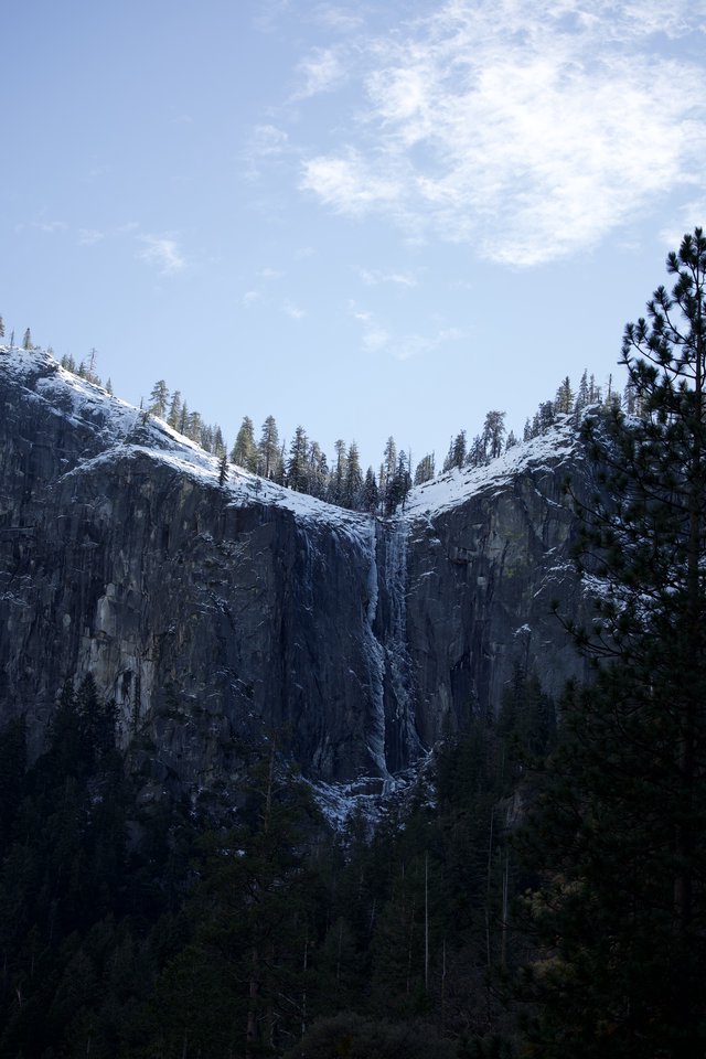 Snowy Waterfall Cascading Down Dark Granite Cliffs
