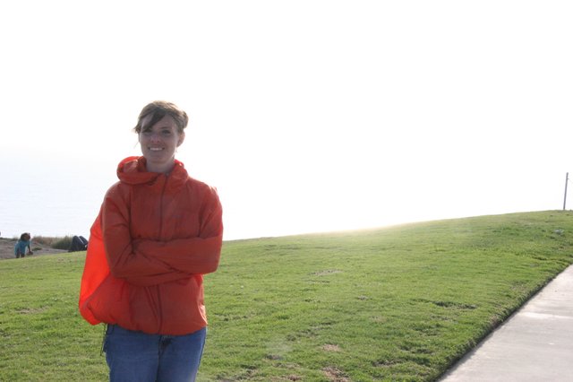 Woman in Red Jacket Smiling at Coastal Park