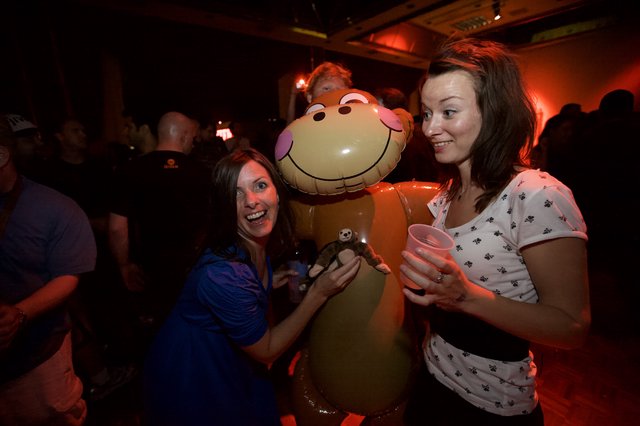 Two Women Laughing with Inflatable Monkey at Party
