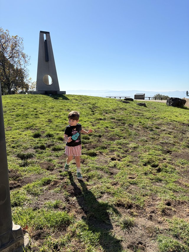 Child Exploring Near Modern Monument on Hillside