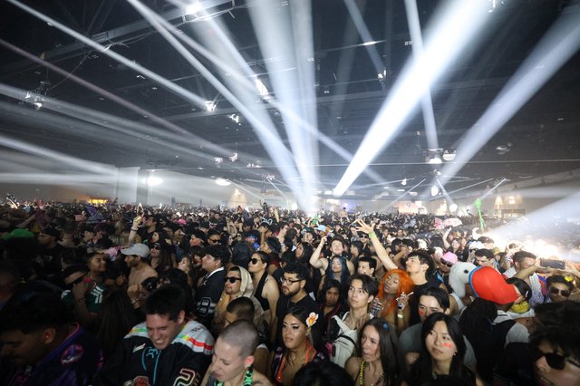 Massive Indoor Rave Crowd Bathed in Spectacular Light Beams