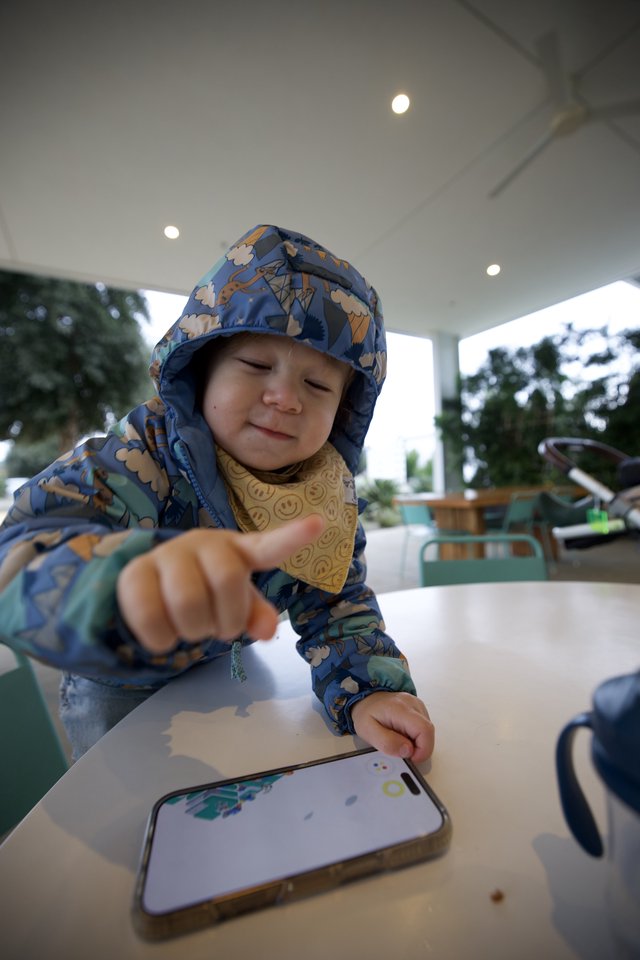 Young Child Engaging with Smartphone at Outdoor Table