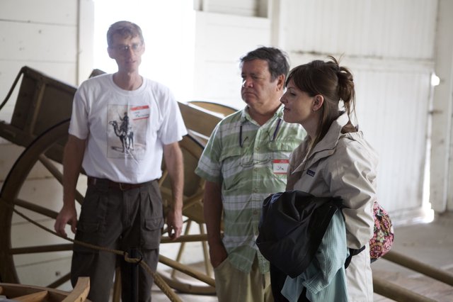 Three Visitors Examine Historic Wagon at Museum