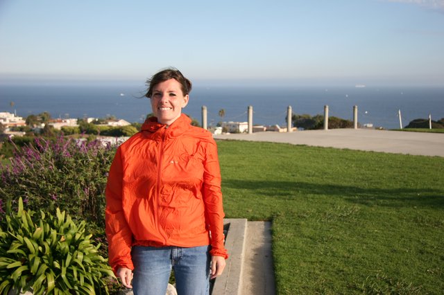 Smiling Woman in Orange Jacket by the Sea