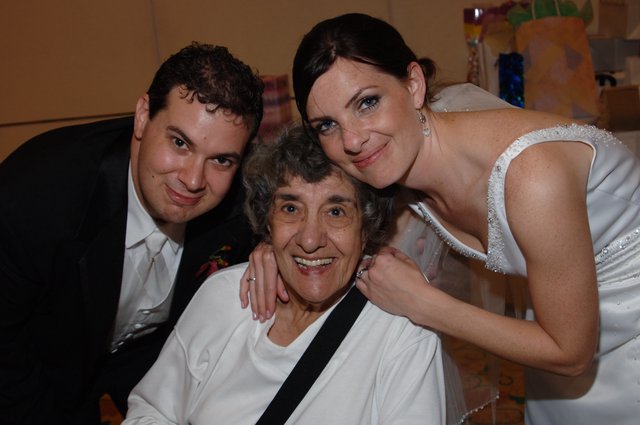 Bride and Groom Embrace Beloved Grandmother at Wedding