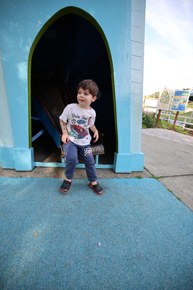 Young Boy at Colorful Playground Tunnel Entrance