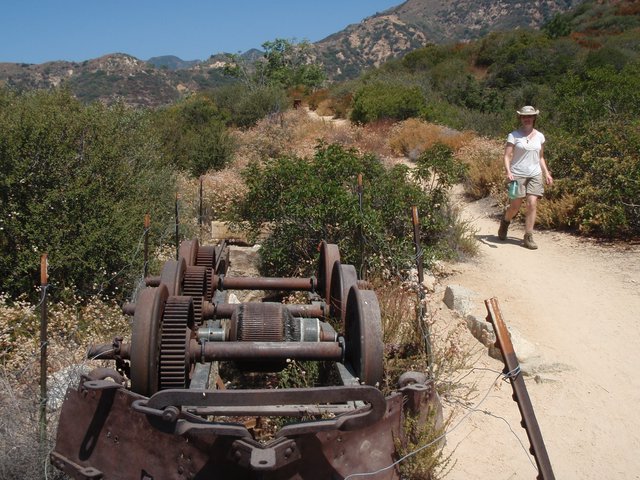Hiker Passes Rusted Mining Equipment on Desert Trail
