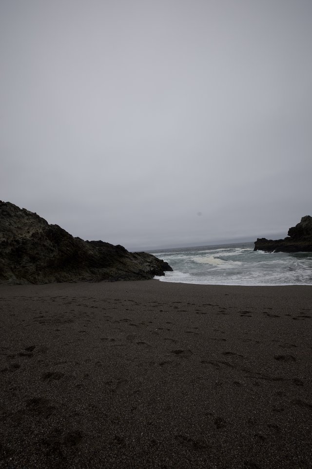 Dark Sand Cove Under Brooding Fog-Shrouded Skies