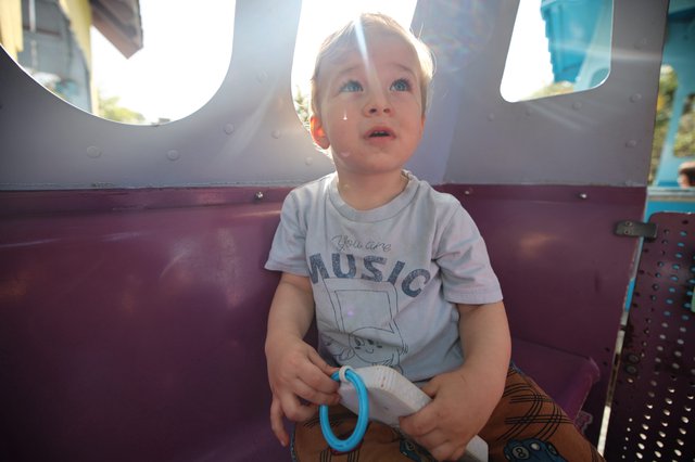 Young Child Gazing Upward on Amusement Park Ride