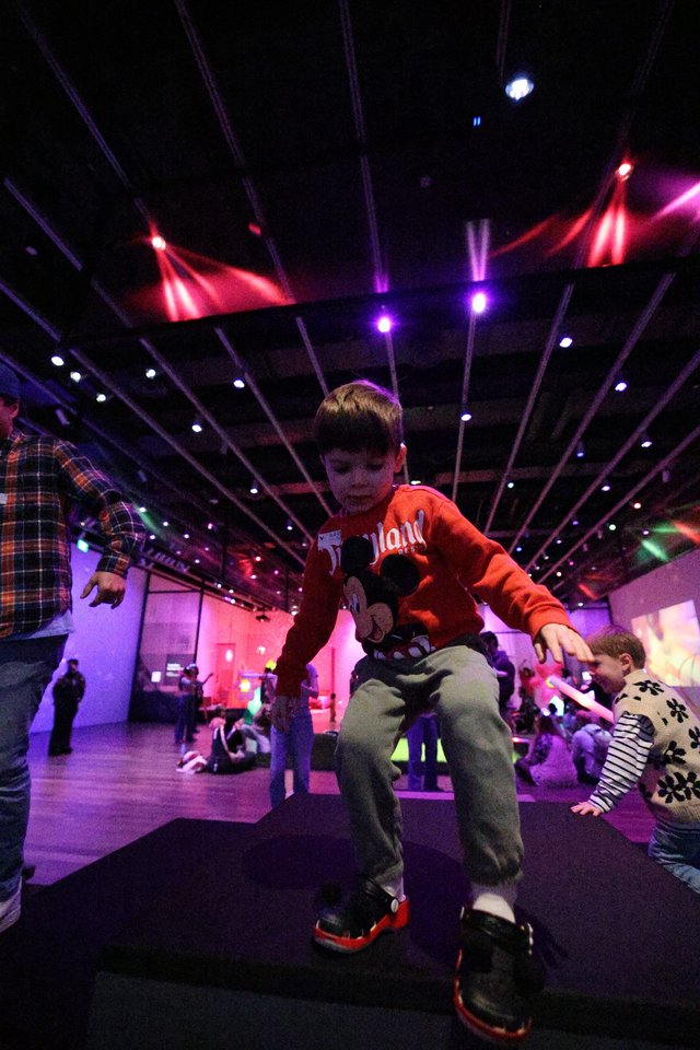 Child Dancing at Baby Rave Event Under Colorful Lights