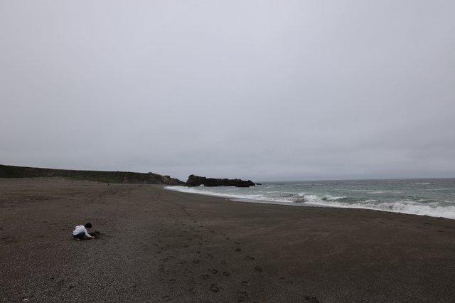 Child Playing Alone on a Moody Coastal Beach