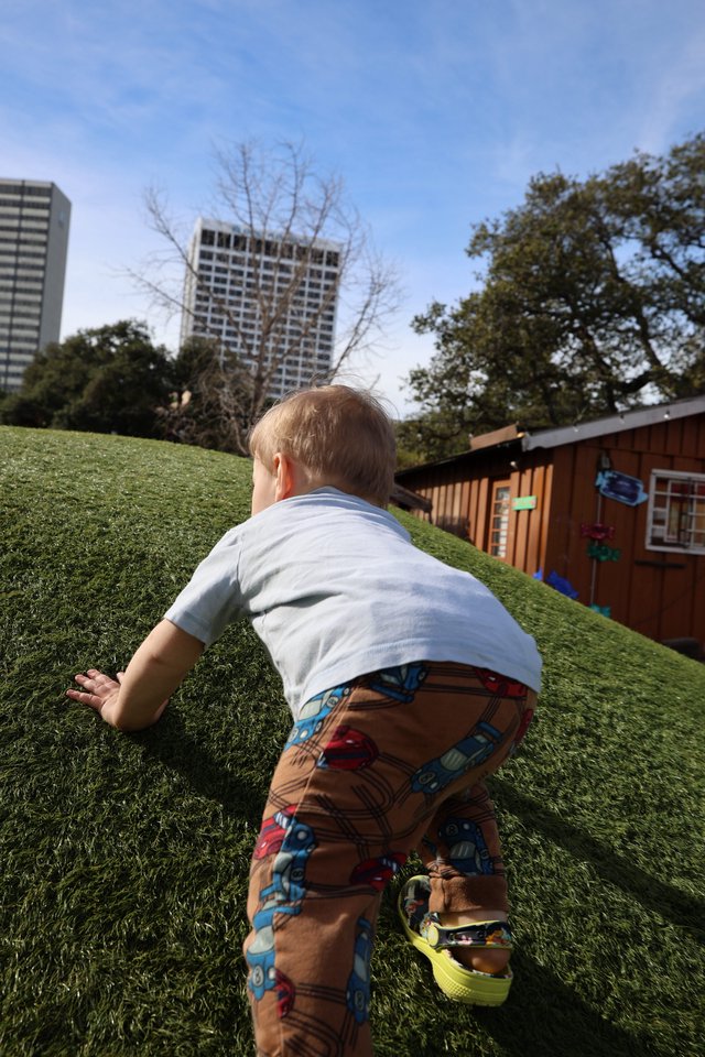 Toddler Climbing Hill in Urban Park Setting