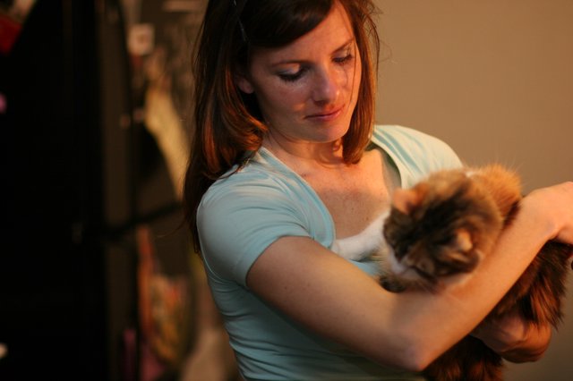 Woman Tenderly Cradling a Fluffy Tabby Cat