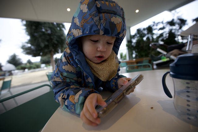 Young Child Using Smartphone at Outdoor Cafe