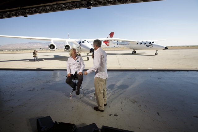 Richard Branson and Friend Relaxing Near White Knight Two Plane at Airport