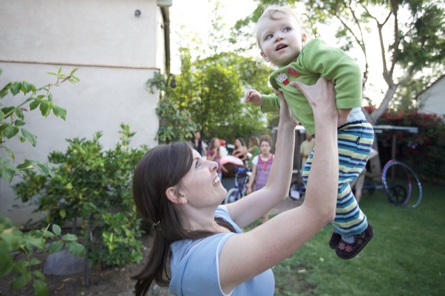 Joyful Mother Lifts Baby High in Backyard