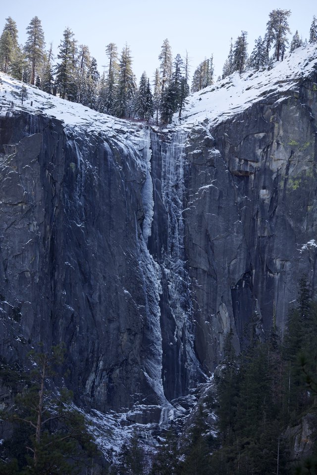 Frozen Waterfall Cascading Through Snow-Covered Granite Cliffs