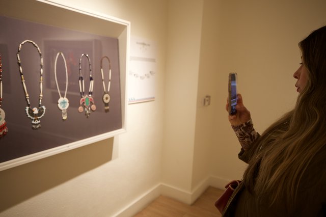 Visitor Photographing Native American Jewelry Display in Museum