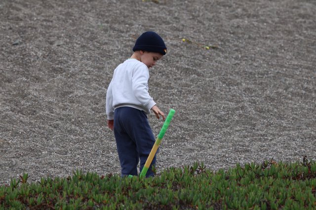 Young Boy Playing With Toy Bat on Sandy Shore