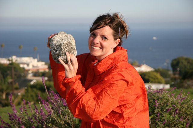 Woman Proudly Displays Large Rock by the Sea