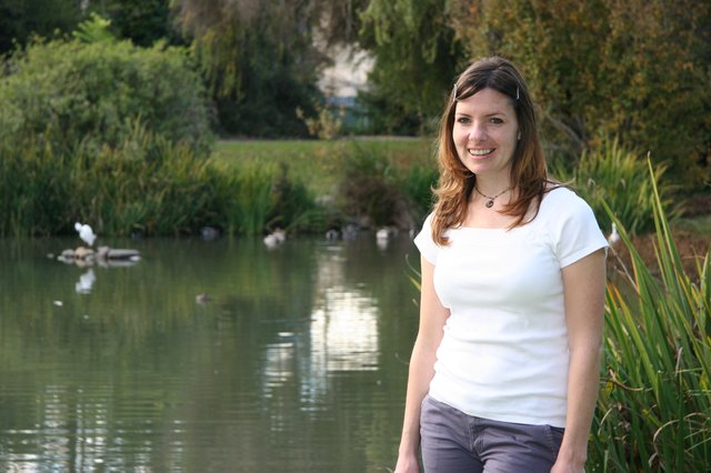 Smiling Woman by a Tranquil Park Pond